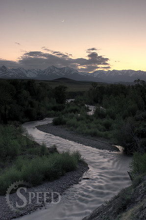 A crescent moon rises over Big Timber Creek and the Crazy Mountains.
