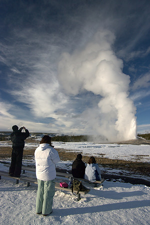 Tourists watching old faithful in Winter.