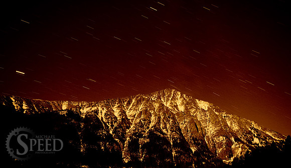 Amber colored star trails over big timber peak.